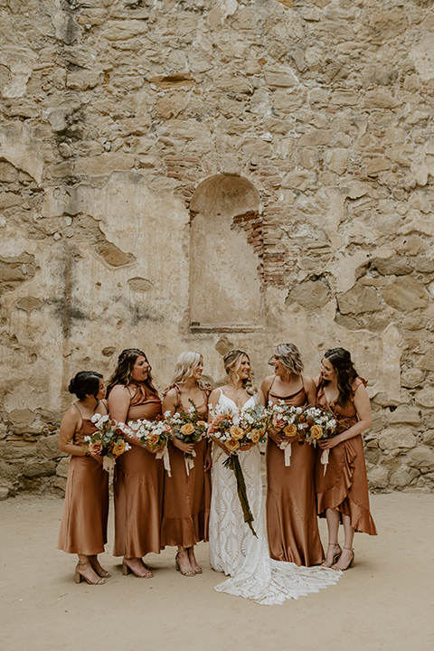 Bridesmaids in mismatched terracotta dresses celebrating with the bride at a boho rustic wedding