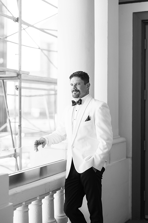 The groom poses at the US Grant House, looking sophisticated in a crisp white tuxedo jacket paired with classic black trousers. His timeless style exudes modern elegance and charm.