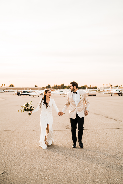 Bride and groom pose in front of a sleek black helicopter at Hangar 21, with the groom dipping the bride for a passionate kiss.