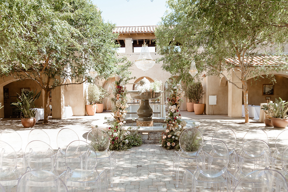 ceremony space with acrylic chairs, grand florals, and rustic charm