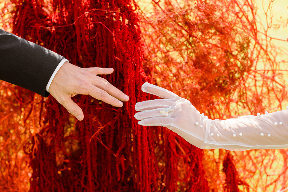 Close-up of the bride’s elegant pearl-adorned dress and opera gloves.