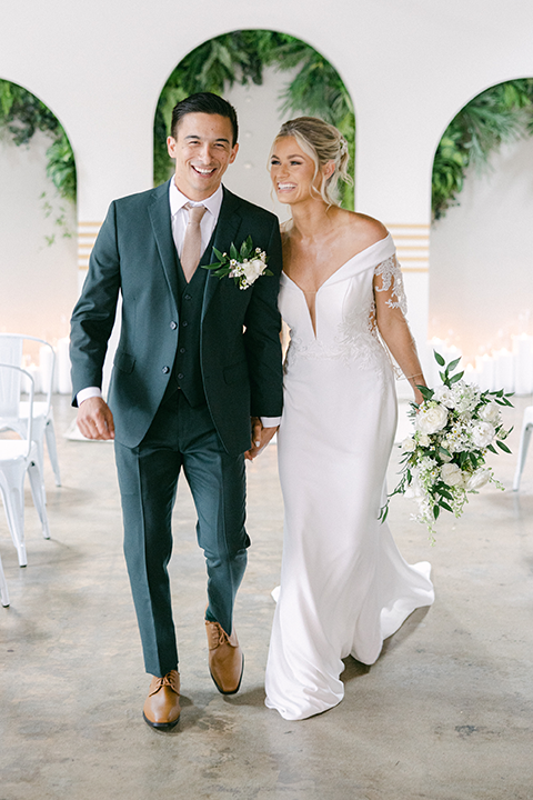 Bride in an off-the-shoulder wedding gown holding a white floral bouquet.
