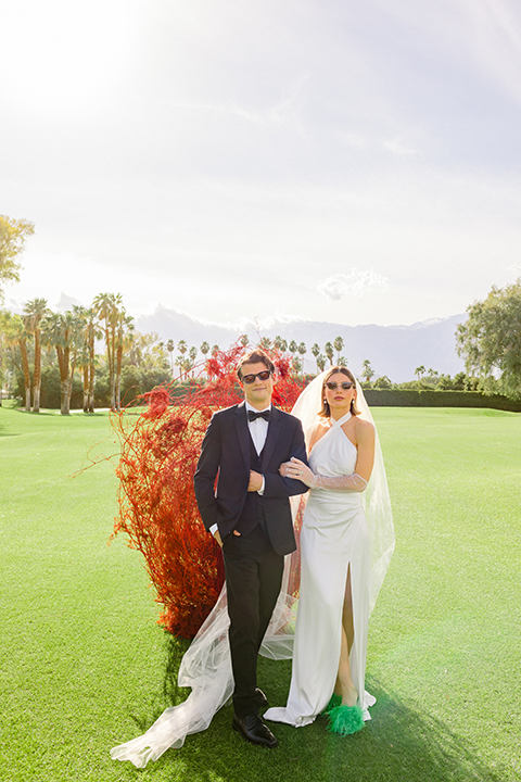 A chic wedding editorial featuring a bride in a pearl-detailed gown with black gloves and a groom in a black tuxedo.