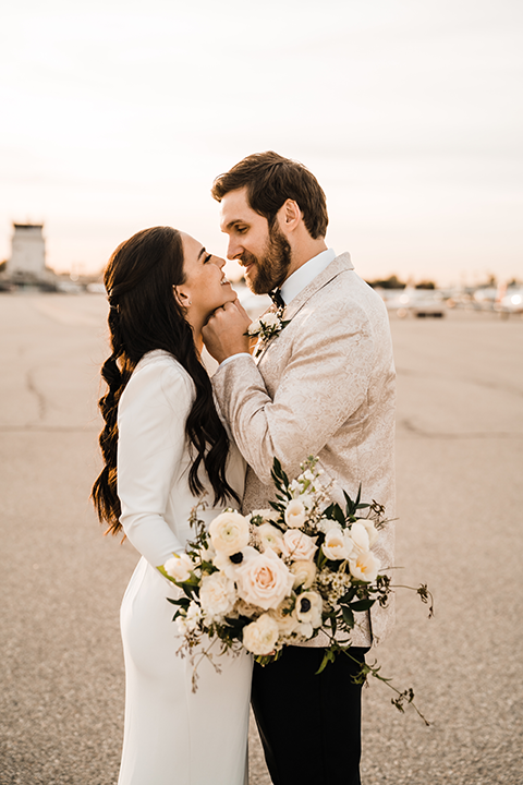 Bride and groom pose in front of a sleek black helicopter at Hangar 21, with the groom dipping the bride for a passionate kiss.