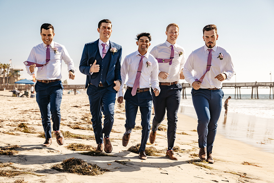groomsmen running on the sand