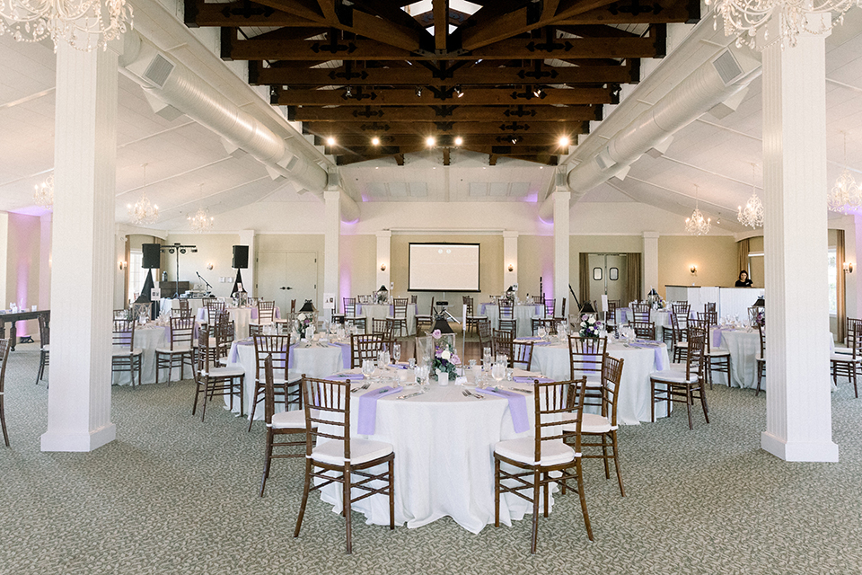 Reception decor with white table linens and purple decor elements