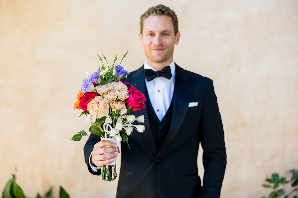 groom holiding out a florla bouquet to the camera