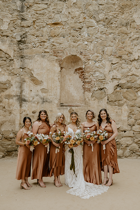 Bridesmaids in mismatched terracotta dresses celebrating with the bride at a boho rustic wedding
