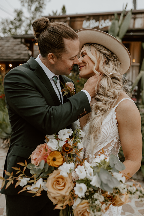 Couple sharing a romantic kiss at their rustic boho wedding, surrounded by natural greenery and soft, warm lighting