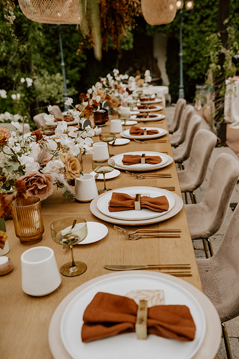 Warm and inviting rustic boho wedding reception setup with wooden tables, candles, and floral centerpieces, creating a cozy, intimate atmosphere