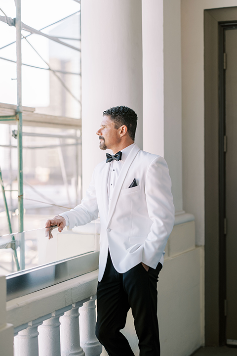 The groom poses at the US Grant House, looking sophisticated in a crisp white tuxedo jacket paired with classic black trousers. His timeless style exudes modern elegance and charm.