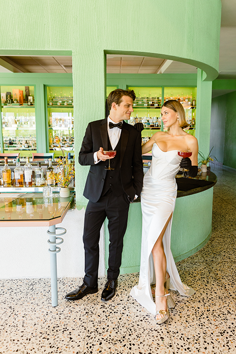 A chic wedding editorial featuring a bride in a pearl-detailed gown with black gloves and a groom in a black tuxedo.