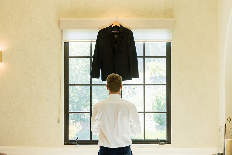 groom looking at the tuxedo he rented from friar tux