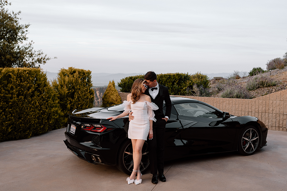 Bride and groom pose with camero