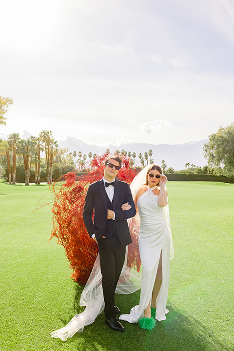 A chic wedding editorial featuring a bride in a pearl-detailed gown with black gloves and a groom in a black tuxedo.