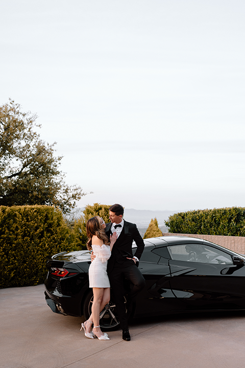 Bride and groom pose with car